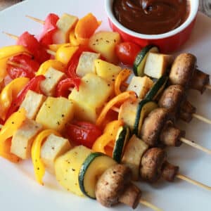 Vegetable skewers on a white plate.