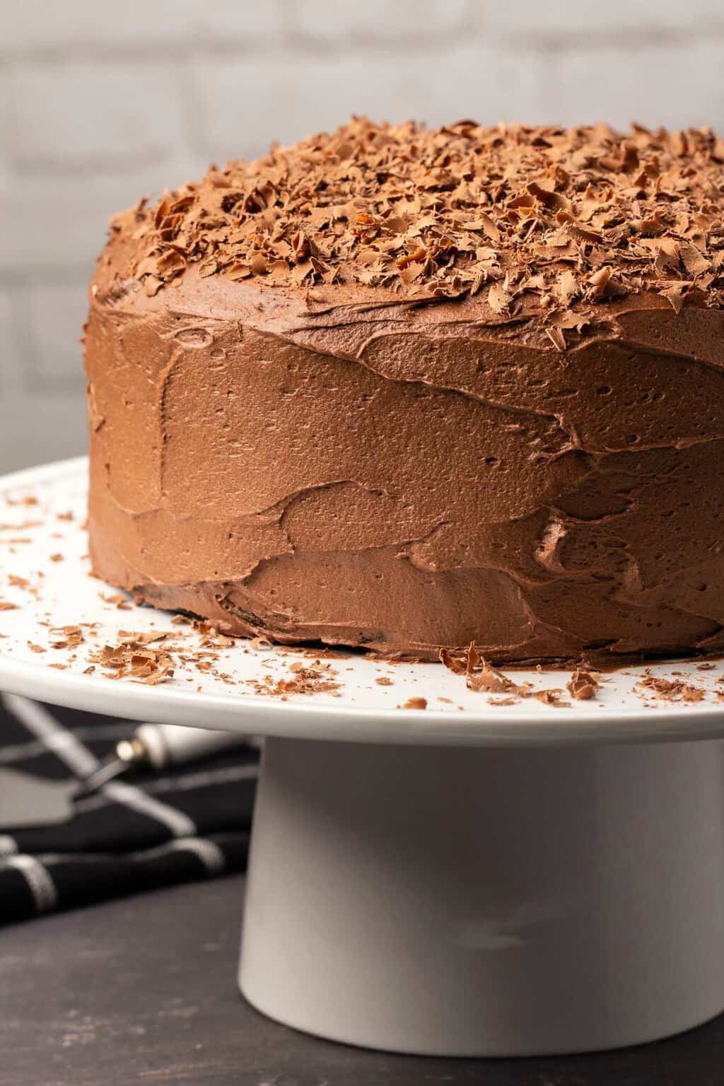 Chocolate cake on a white cake stand. 