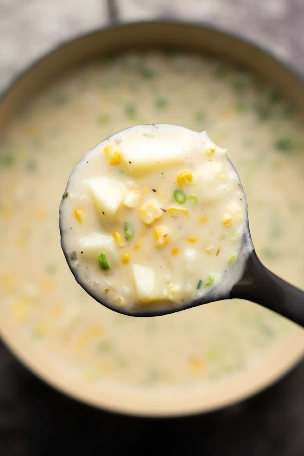 Vegan corn chowder in a pot with a soup ladle. 