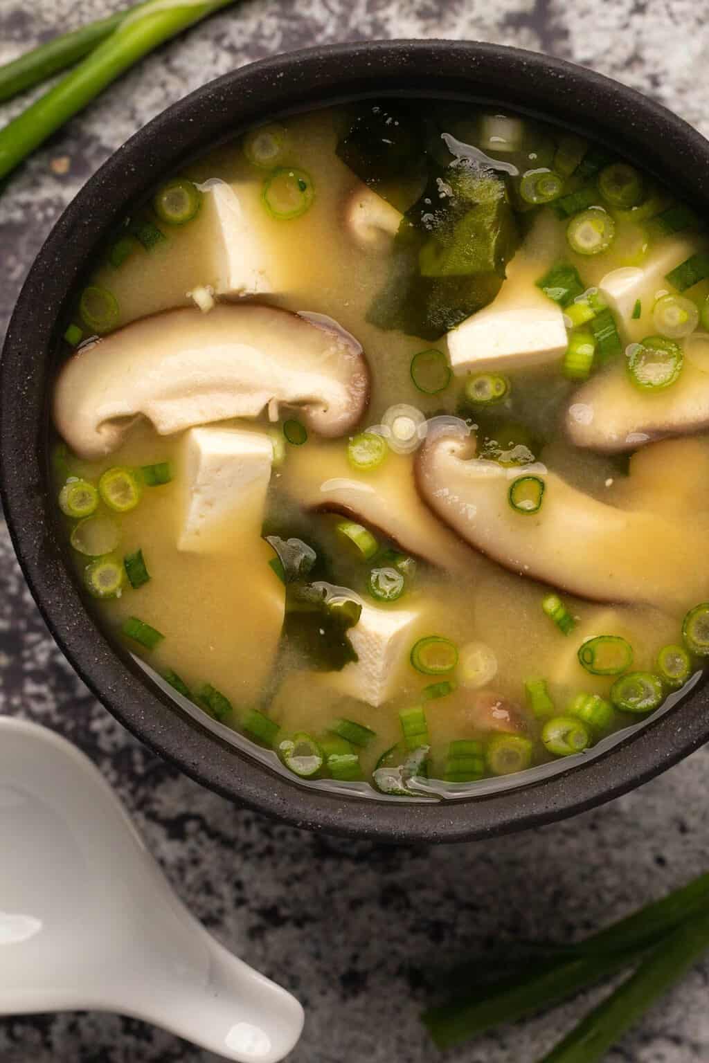 Vegan miso soup in a black bowl. 