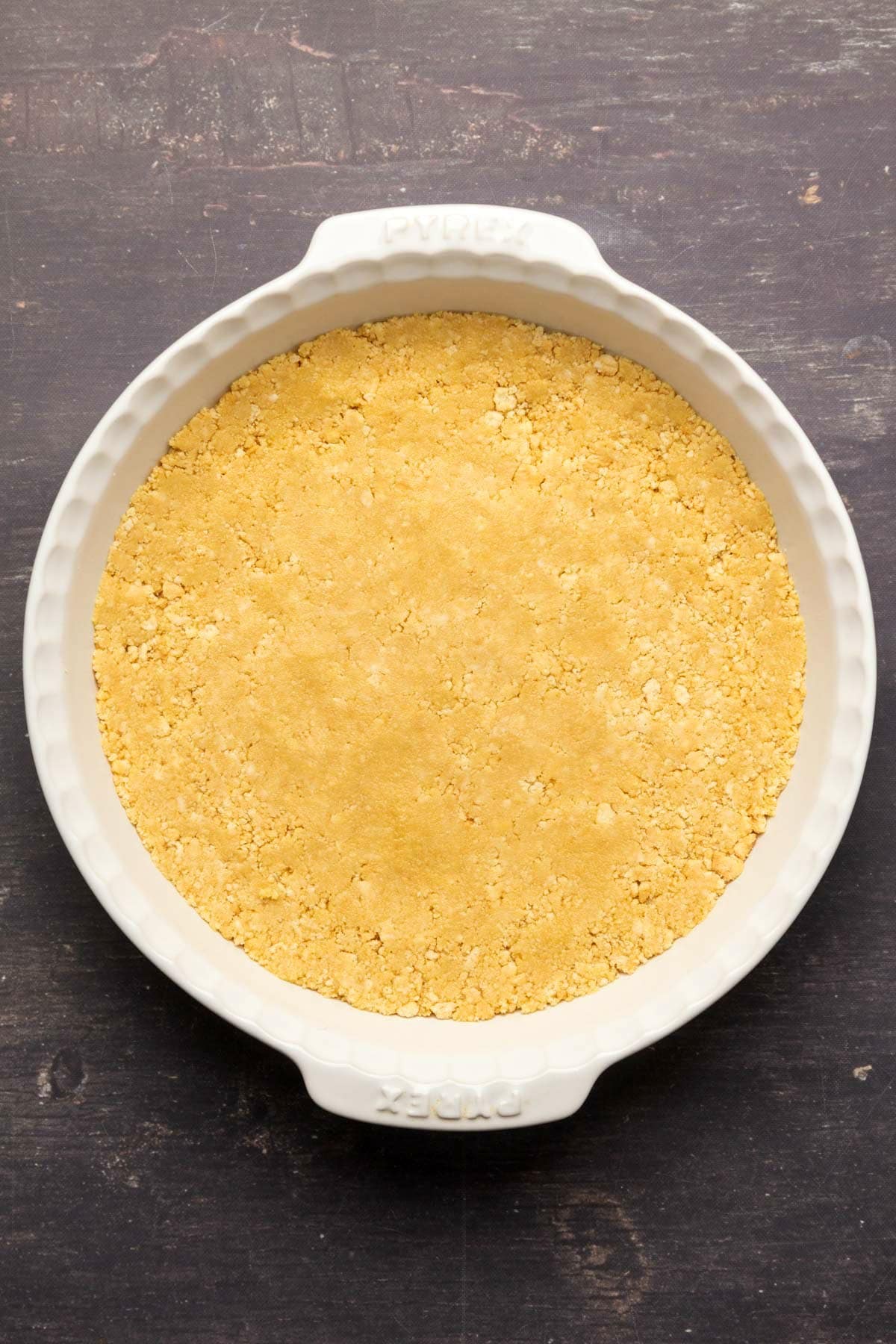 Golden oreo crust pressed down into a white pie dish.