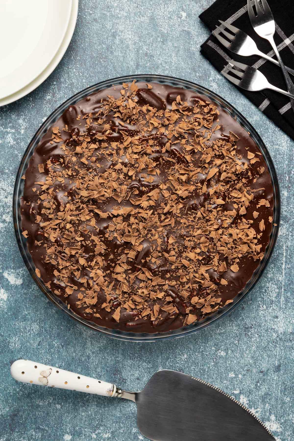 Vegan chocolate tart topped with chocolate shavings in a glass pie dish.
