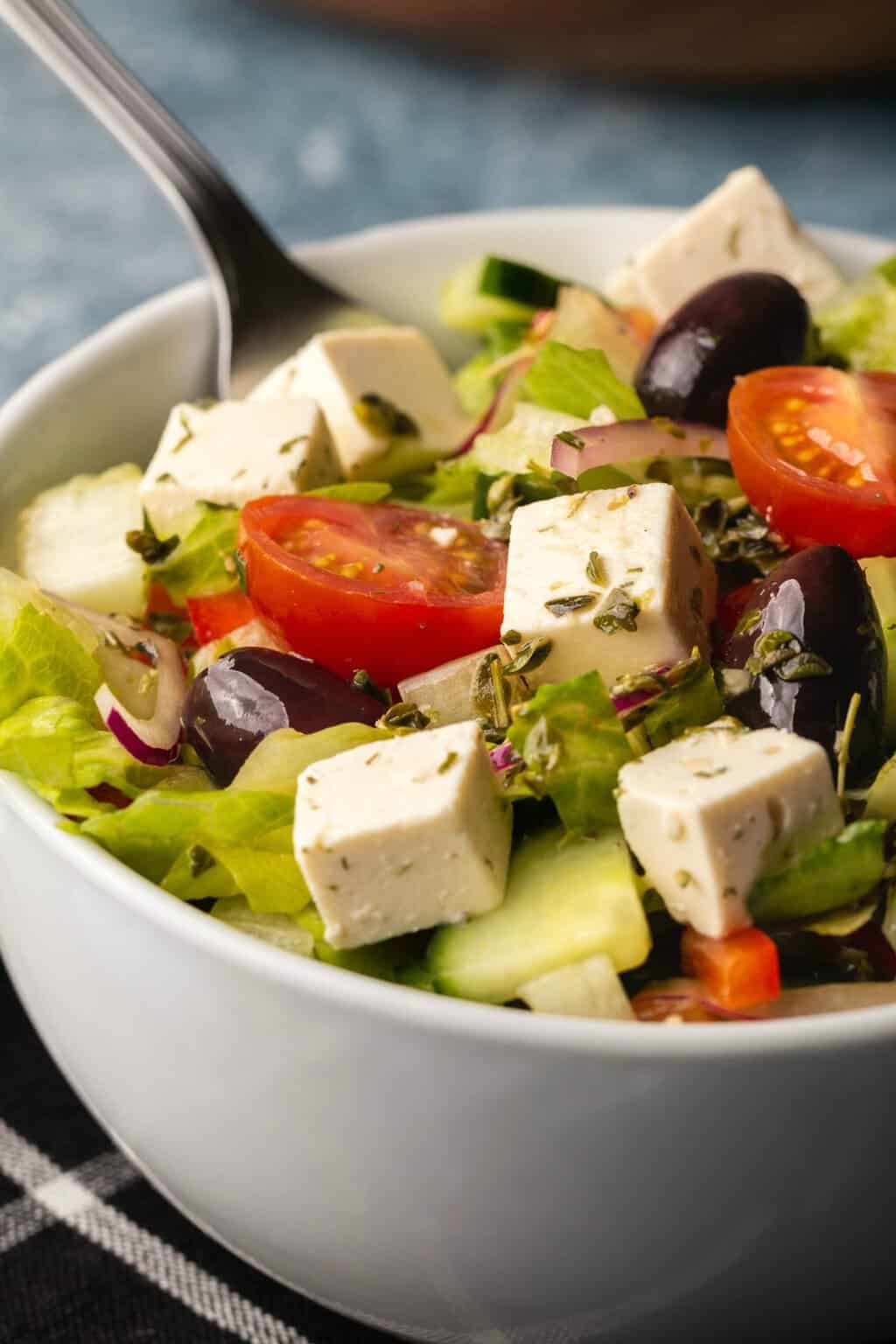 Vegan Greek Salad in a white bowl with a fork. 
