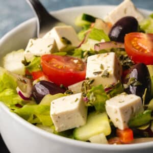 Vegan Greek salad in a white bowl.