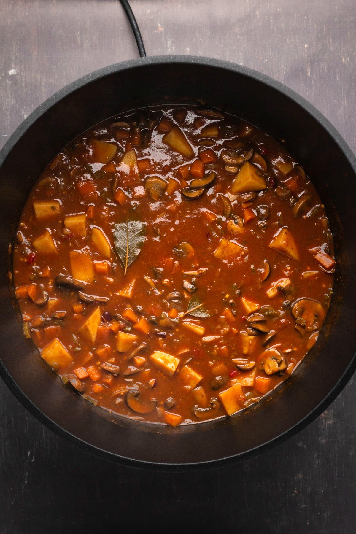 Cooked vegan stew in a black pot. 