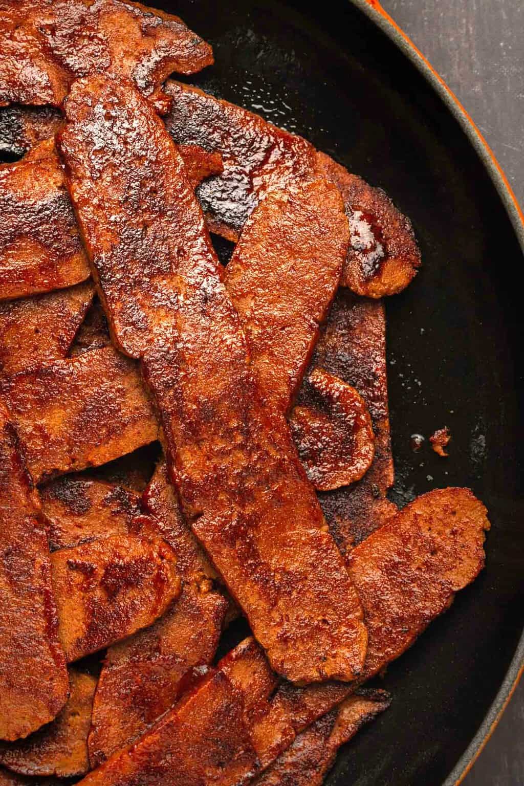 Vegan bacon strips in a frying pan. 