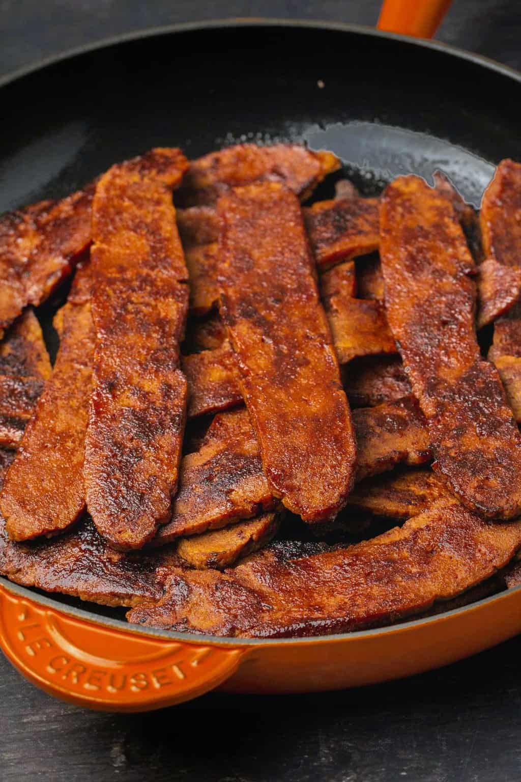 Strips of vegan bacon in a frying pan. 