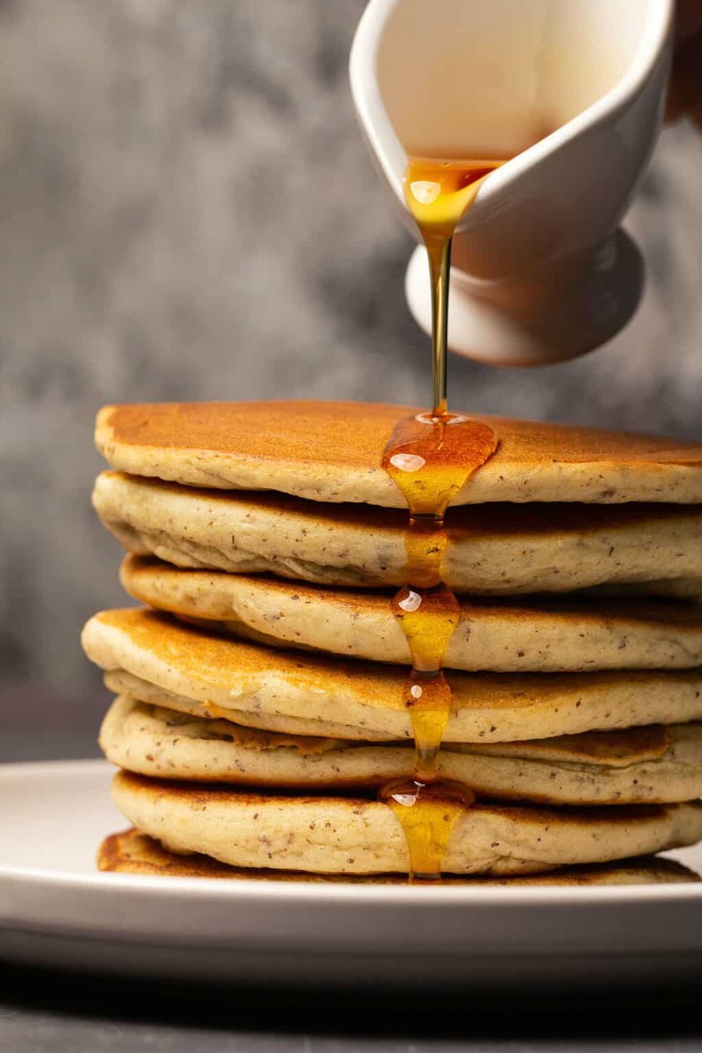 Syrup pouring over a stack of vegan gluten free pancakes.
