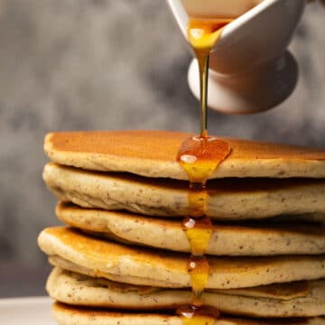 Syrup pouring over a stack of pancakes.
