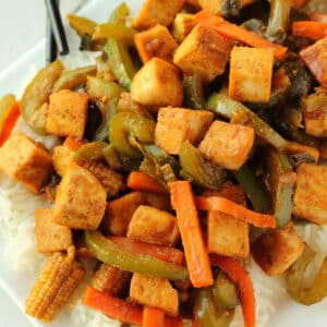 Tofu stir fry with rice on a white plate.