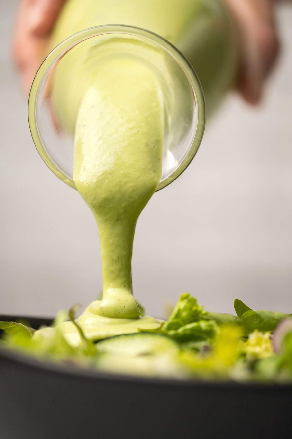 Cashew dressing pouring over a green salad. 