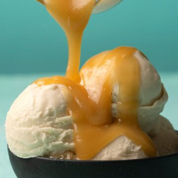 Vegan caramel sauce pouring from a jug over scoops of ice cream.