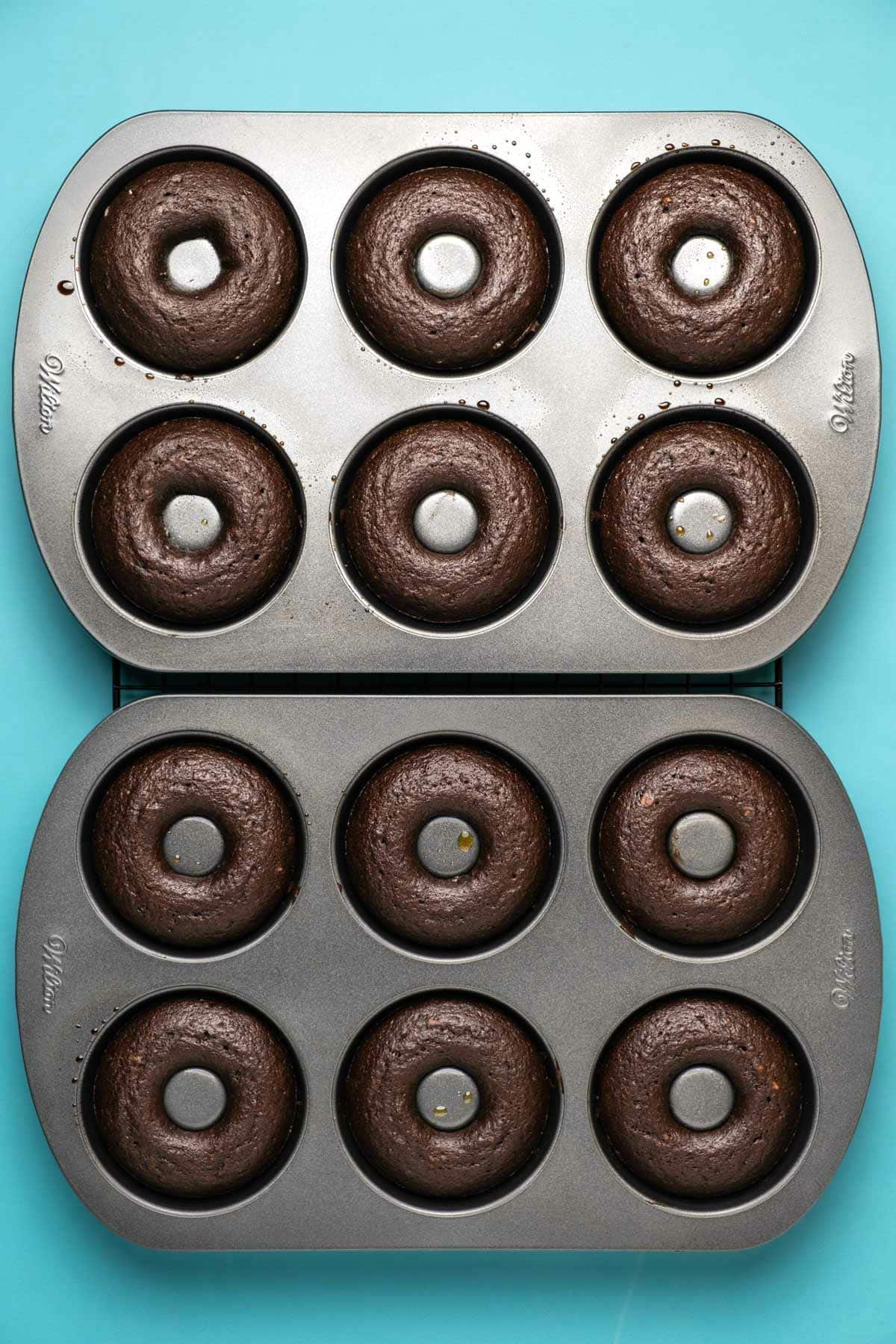 Baked chocolate donuts in donut trays.