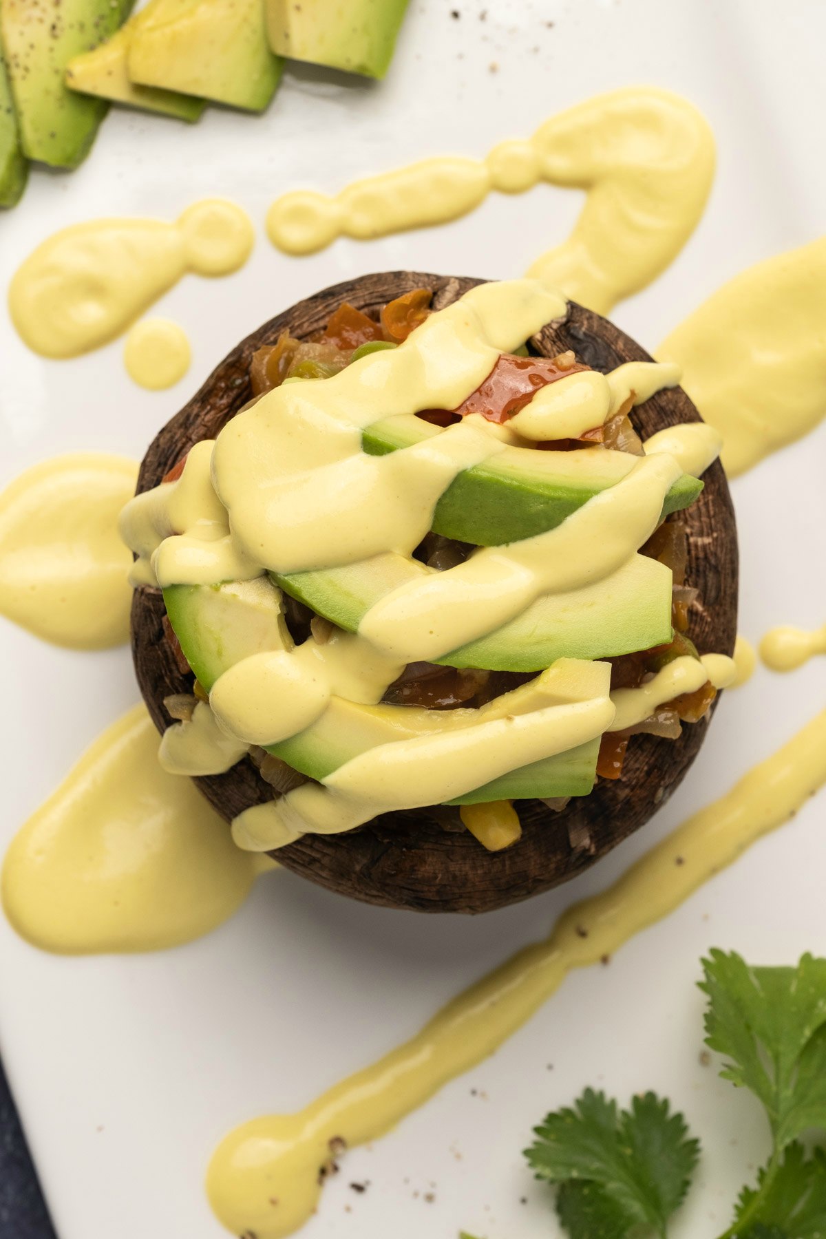 Vegan hollandaise sauce drizzled over a mushroom and vegetable stack. 