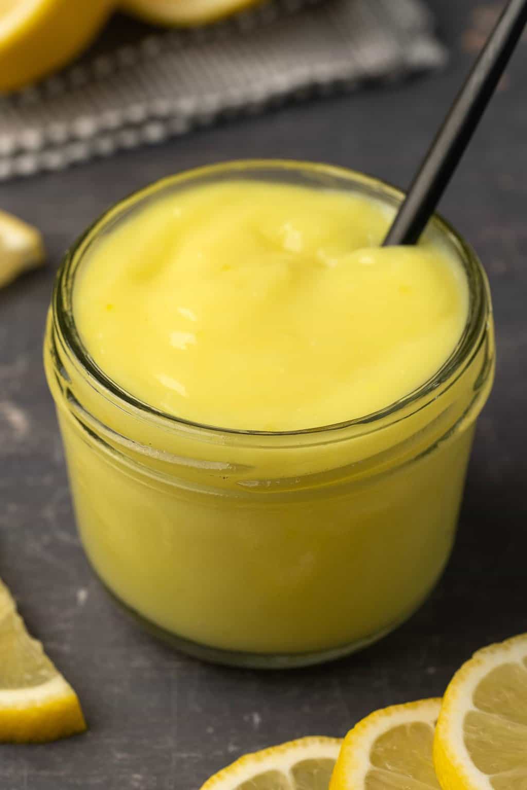 Vegan lemon curd in a glass jar with a spoon. 