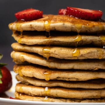 Vegan protein pancakes stacked up on a white plate.