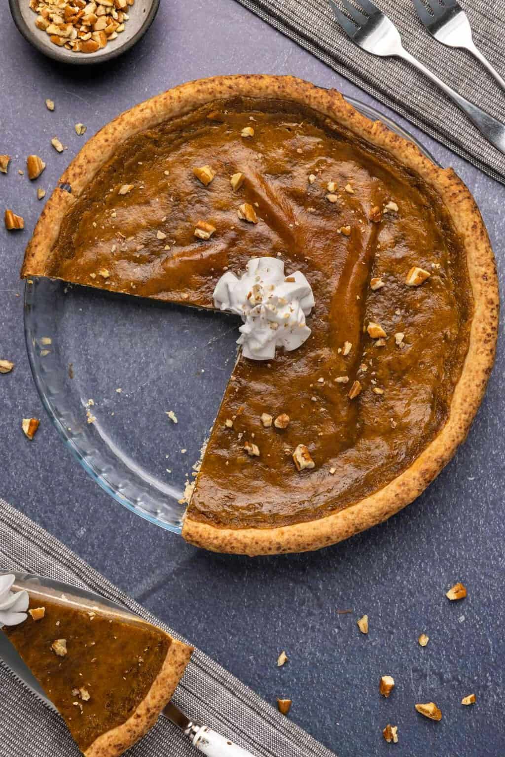 Vegan sweet potato pie in a glass dish with a couple of slices removed. 