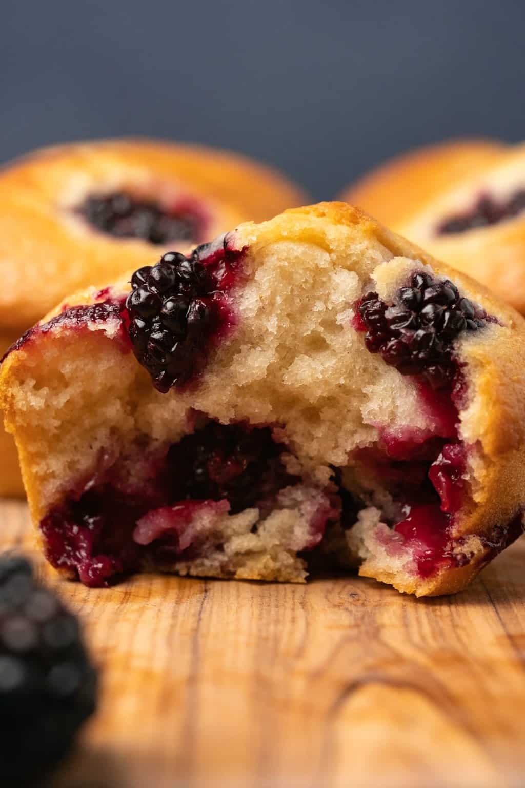 A blackberry muffin broken in half to show the center. 