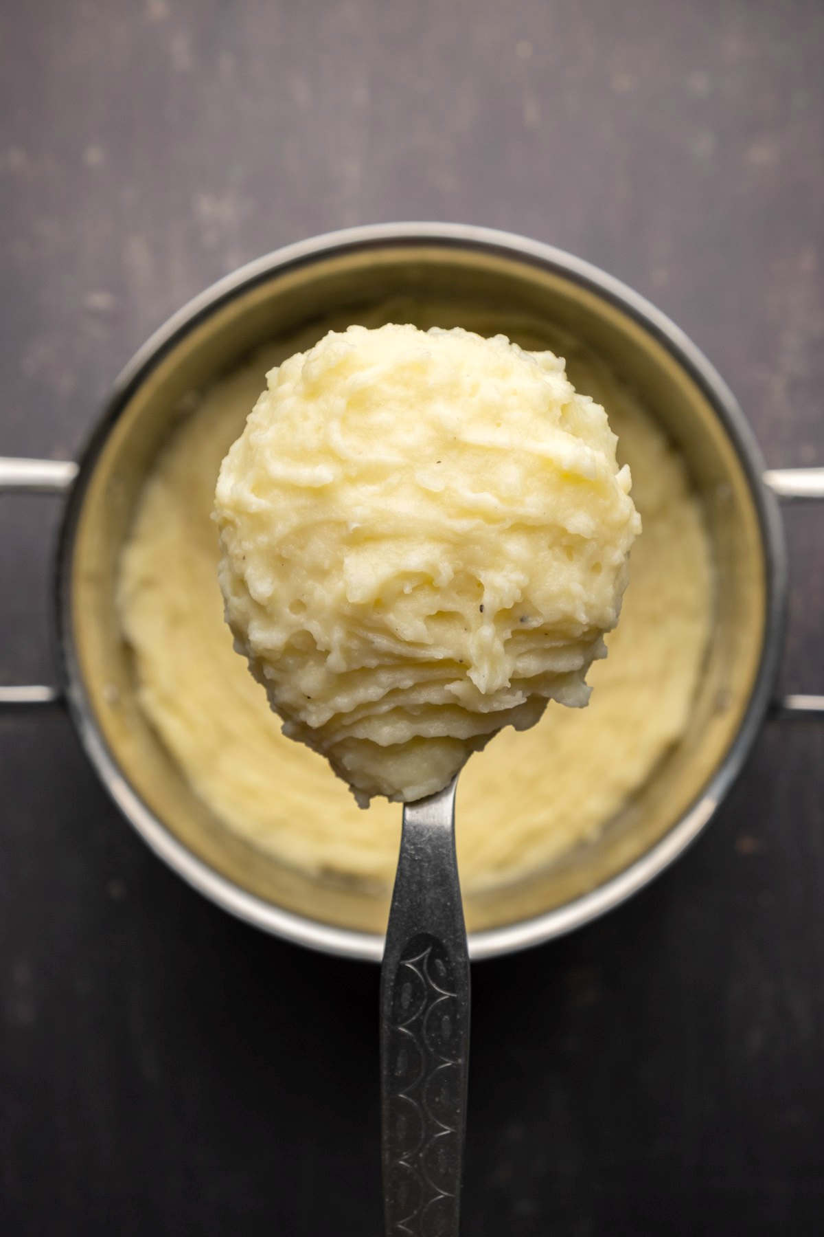 Mashed potatoes in a pot with a serving spoon. 