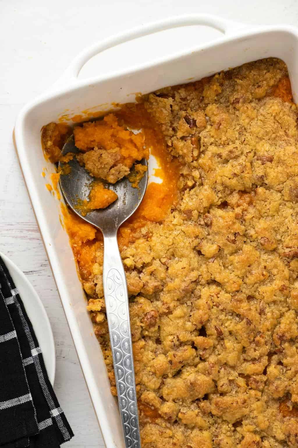Vegan sweet potato casserole in a white dish with a serving spoon. 