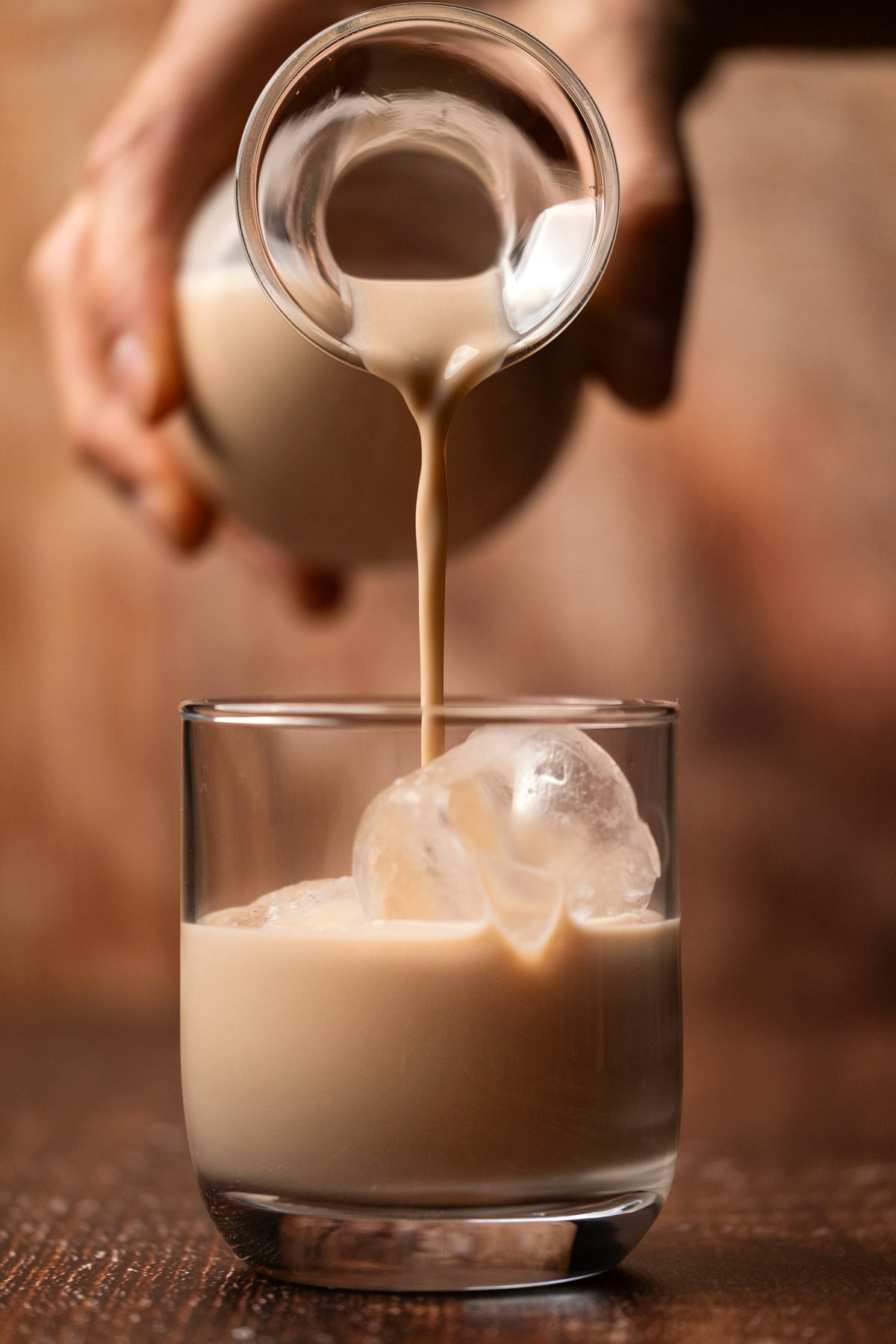 Vegan baileys pouring into a glass with ice. 
