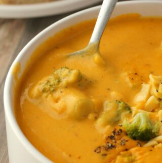 Vegan broccoli cheese soup in a white bowl with a spoon.
