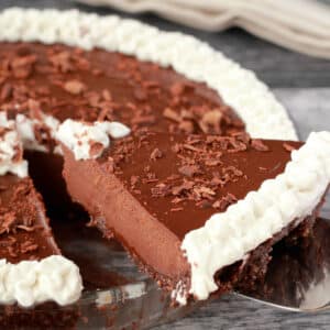 Vegan chocolate pie in a glass pie dish with one slice cut and ready to serve.