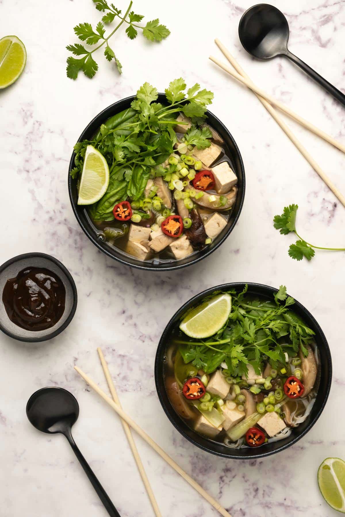 Vegan pho in bowls topped with fresh fresh cilantro and fresh lime.