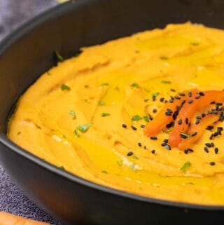 Roasted red pepper hummus in a black bowl.