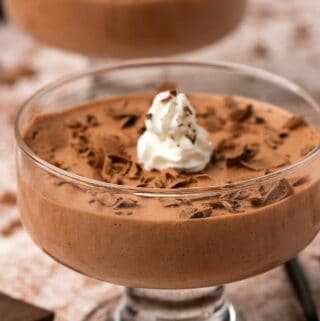 Vegan mousse in serving glasses topped with whipped cream and chocolate shavings.