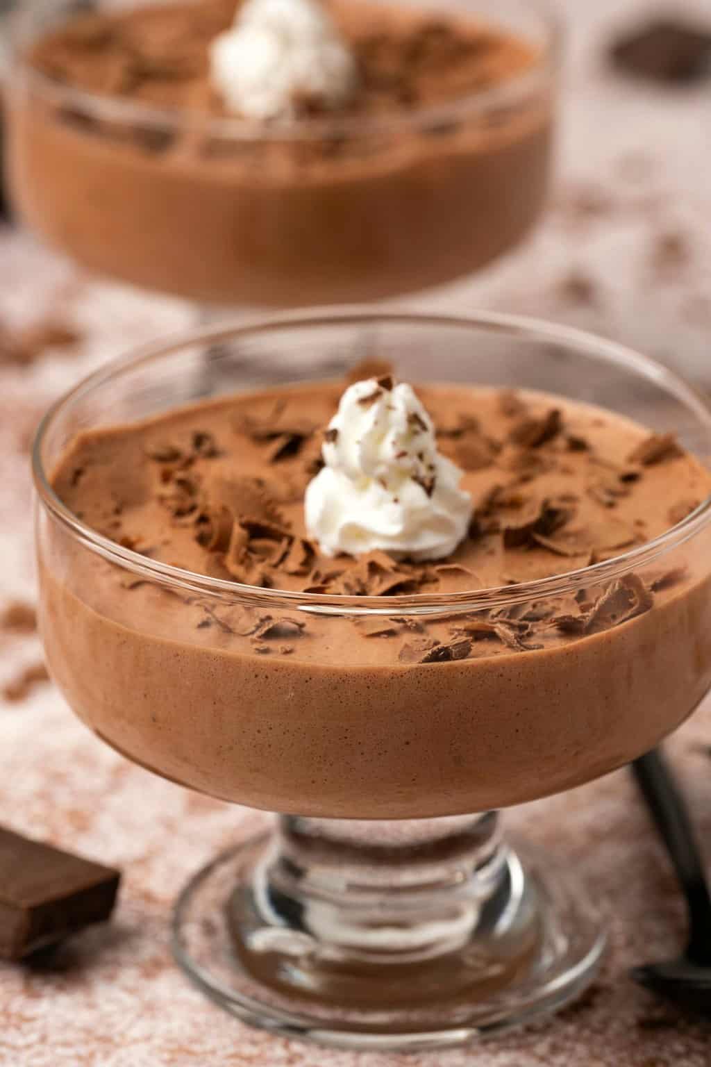 Vegan mousse in glass serving dishes with whipped cream and chocolate shavings. 
