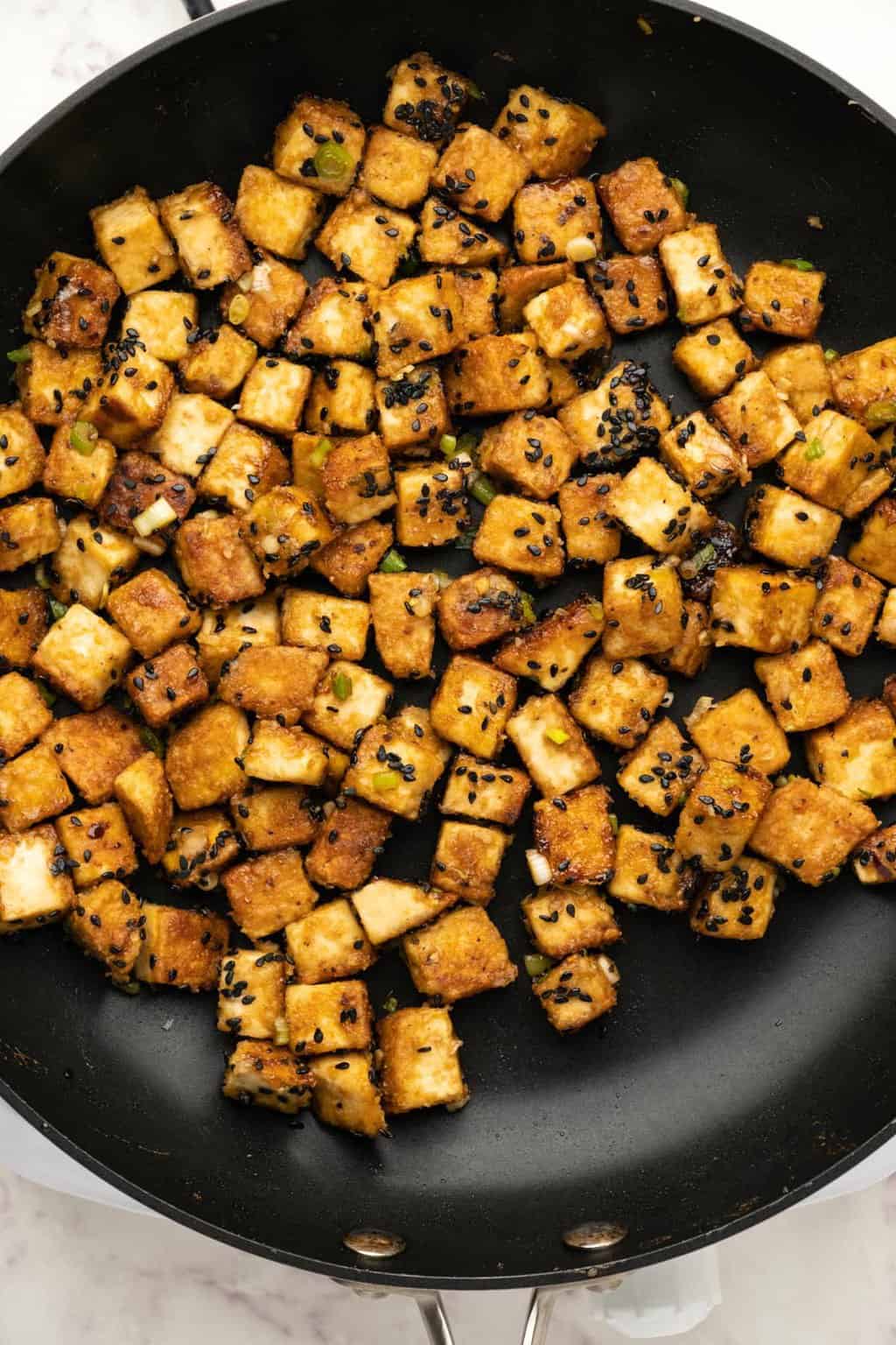 Fried tofu in a black frying pan. 