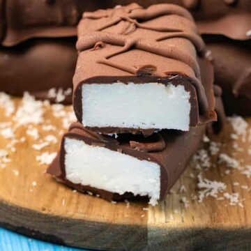 Vegan bounty bars stacked up on a wooden board.