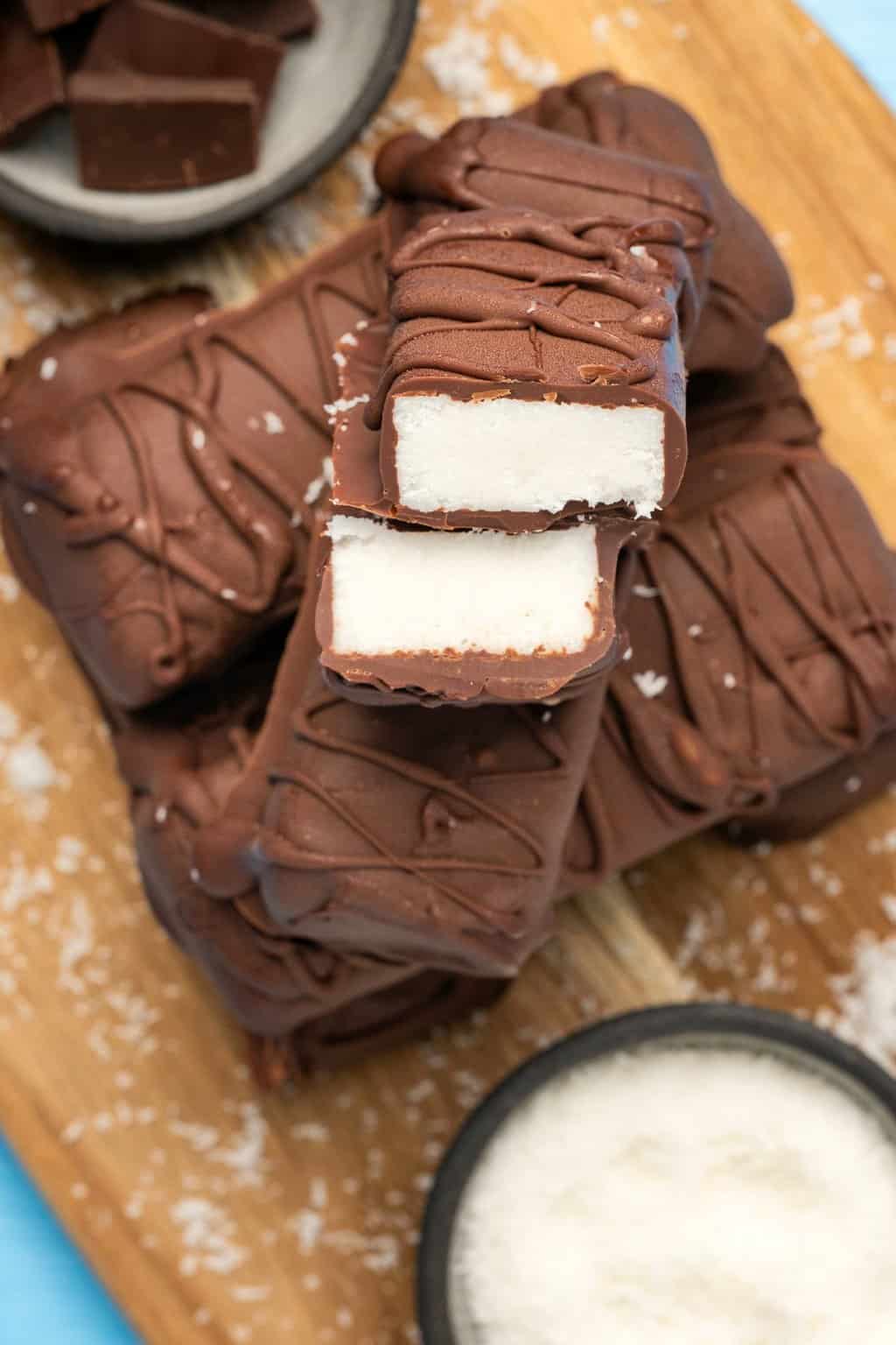 Vegan bounty bars in a stack on a wooden board. 