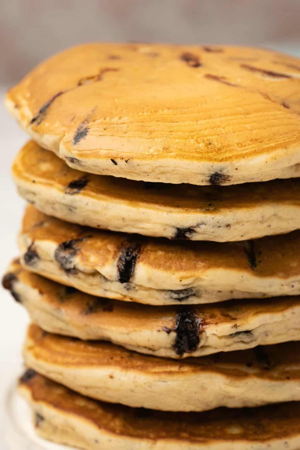 A stack of chocolate chip pancakes on a white plate. 