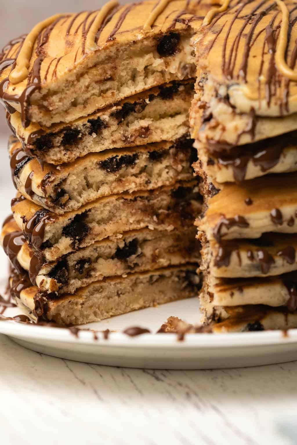 A stack of peanut butter chocolate chip pancakes with a section cut out to show the centers. 