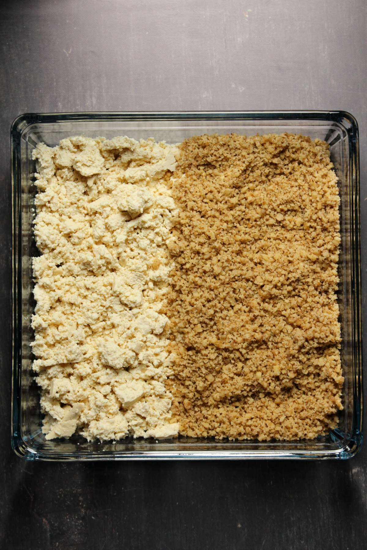 Crumbled tofu and walnuts in a square glass dish.