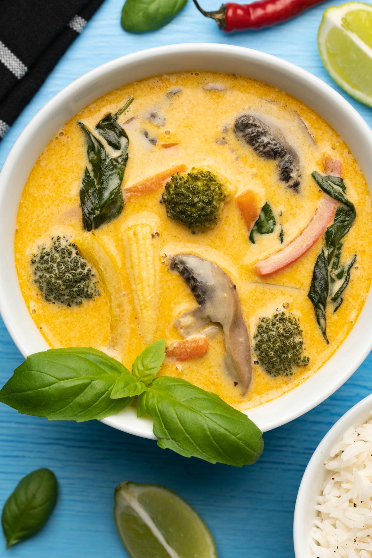 Vegan Thai red curry in a white bowl topped with fresh basil. 