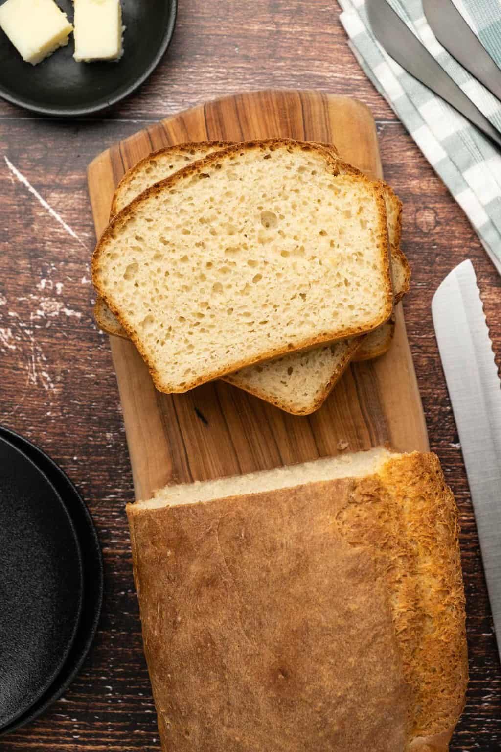 Loaf of bread with slices cut on a wooden board. 