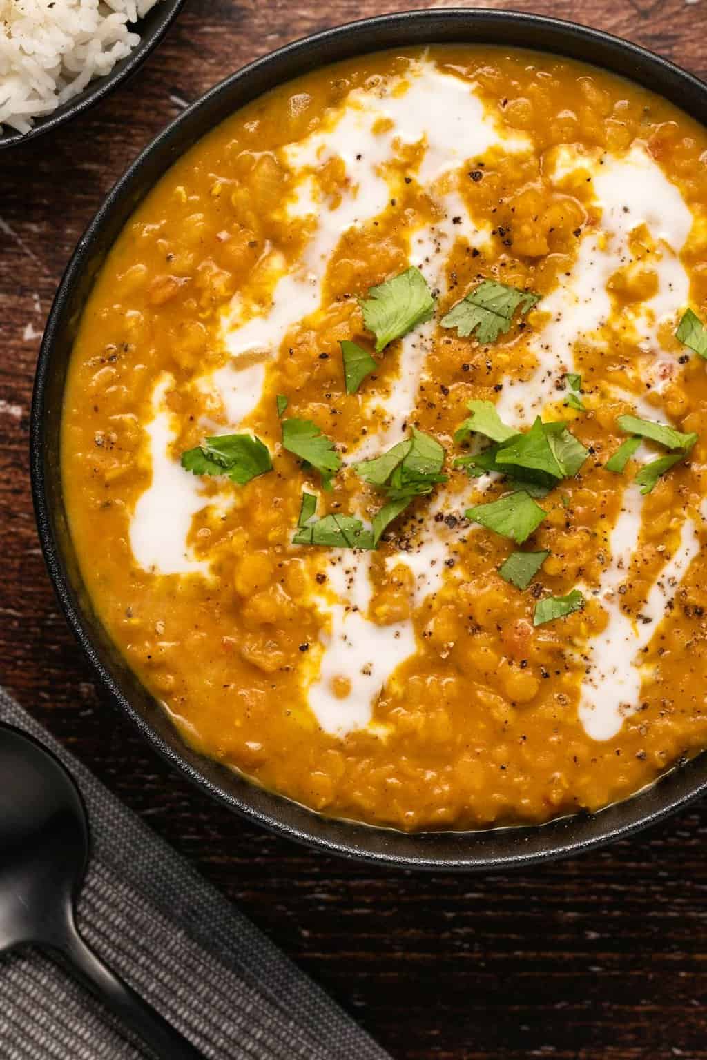 Lentil dal topped with fresh cilantro in a black bowl. 