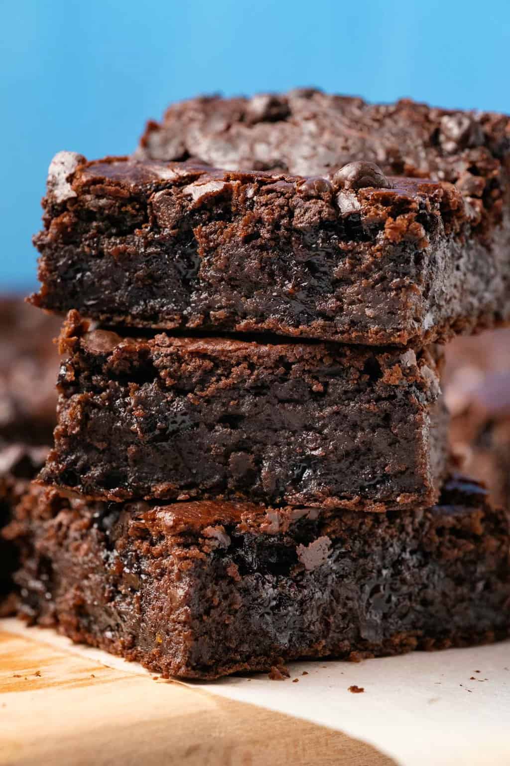 Vegan black bean brownies stacked up on a wooden board. 