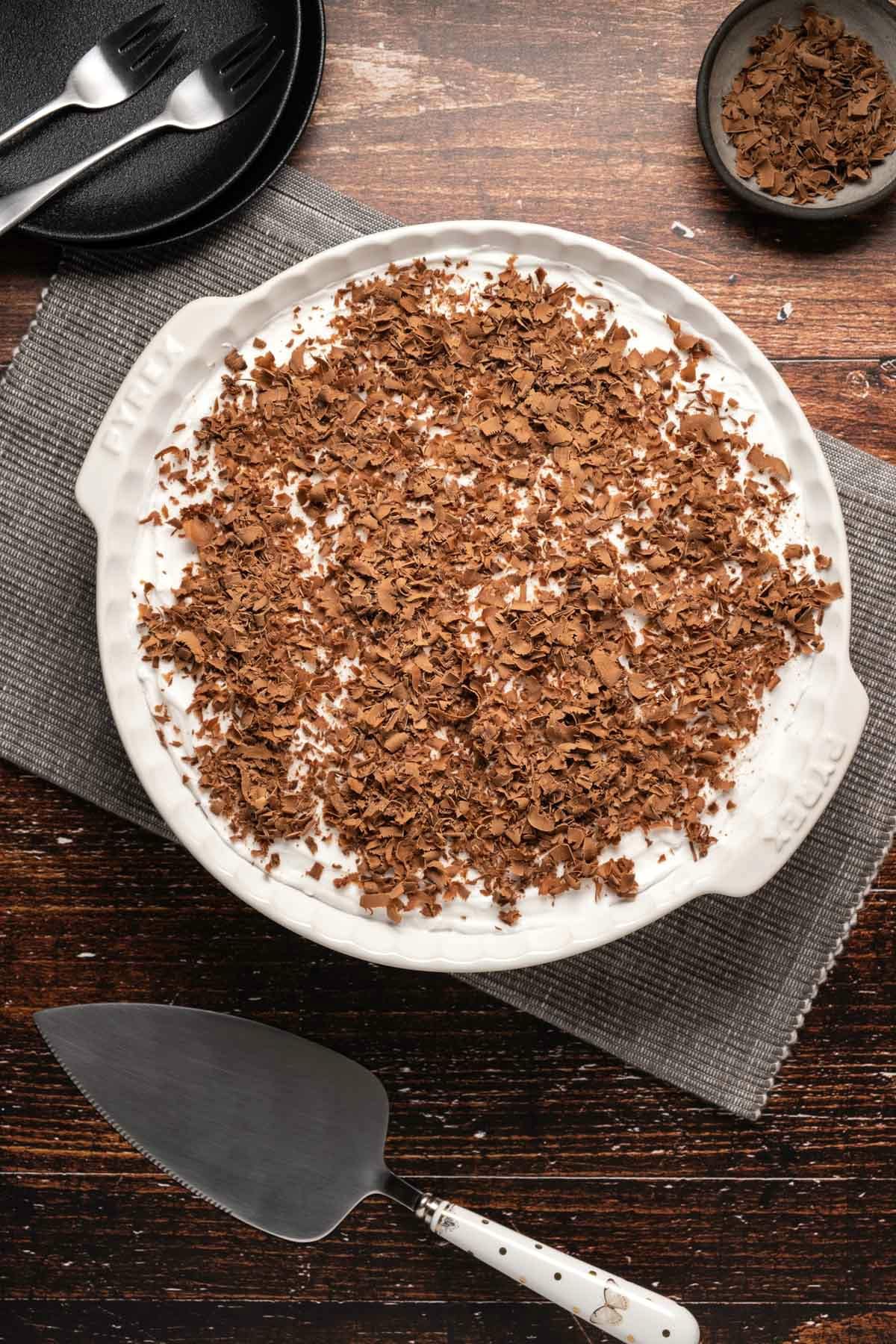 Vegan caramel pie topped with chocolate shavings in a white pie dish.