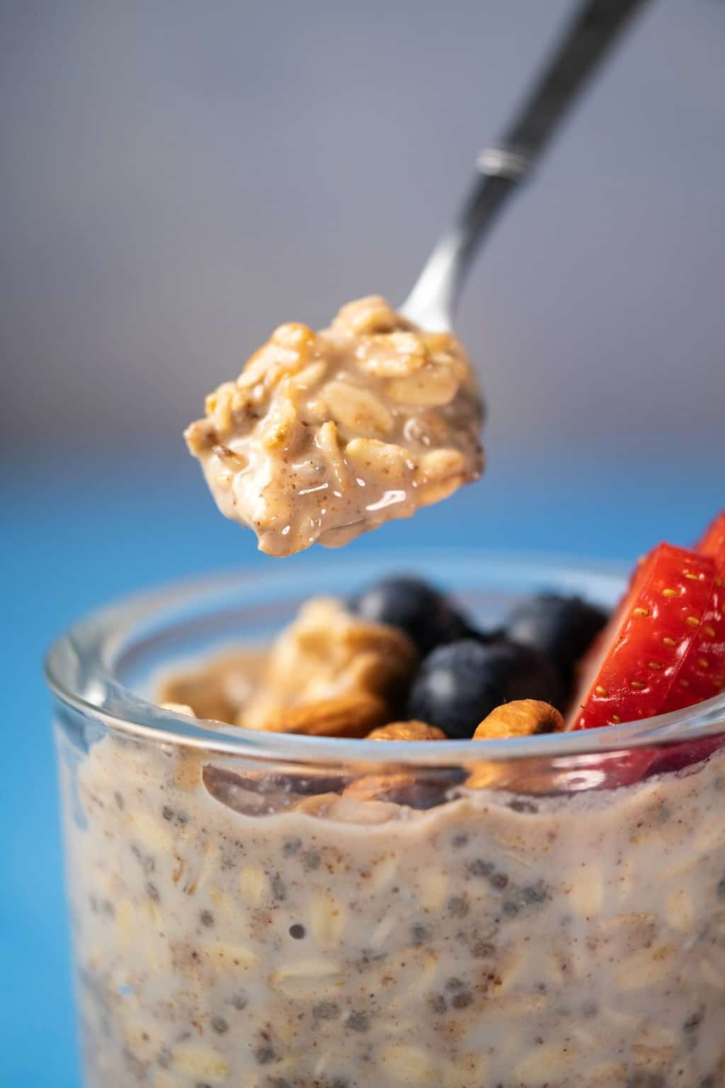Spoonful of overnight oats above a glass jar. 
