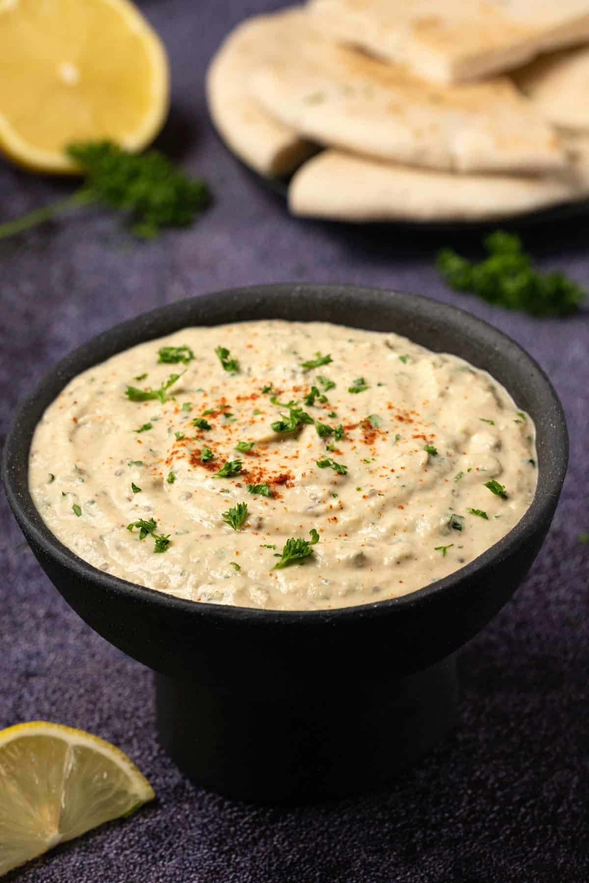 Eggplant dip in a black bowl with chopped parsley. 