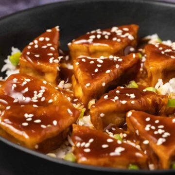 Teriyaki tofu with rice in a black bowl.
