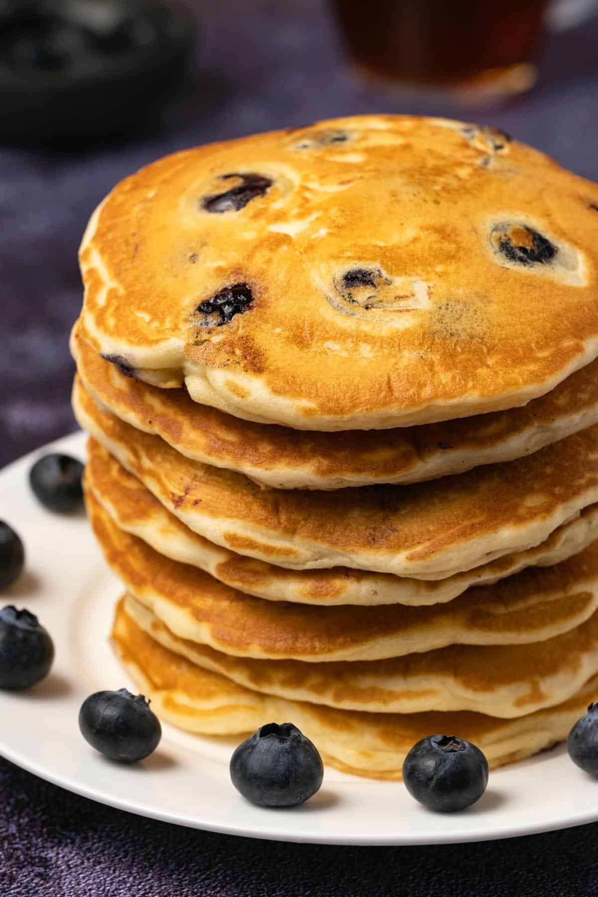 Stack of blueberry pancakes on a white plate. 