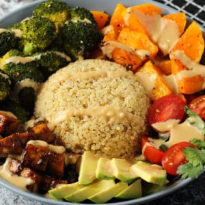 Vegan buddha bowl with roasted veg, quinoa, salad, tofu and tahini sauce.
