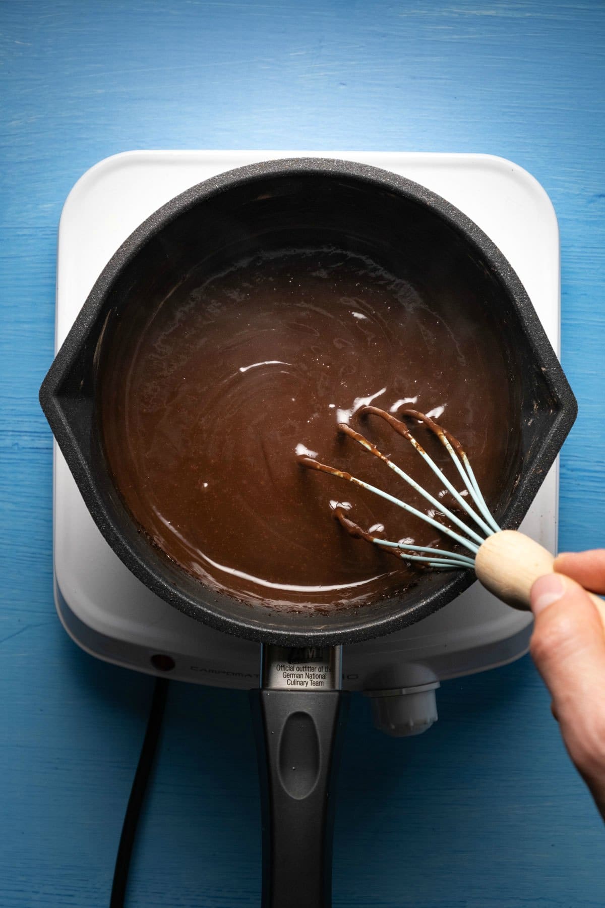 Vegan chocolate pudding in a saucepan with a whisk.