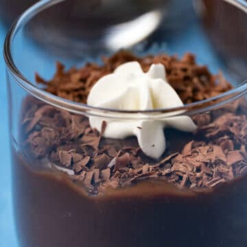Vegan chocolate pudding topped with chocolate shavings and vegan whipped cream in a glass.
