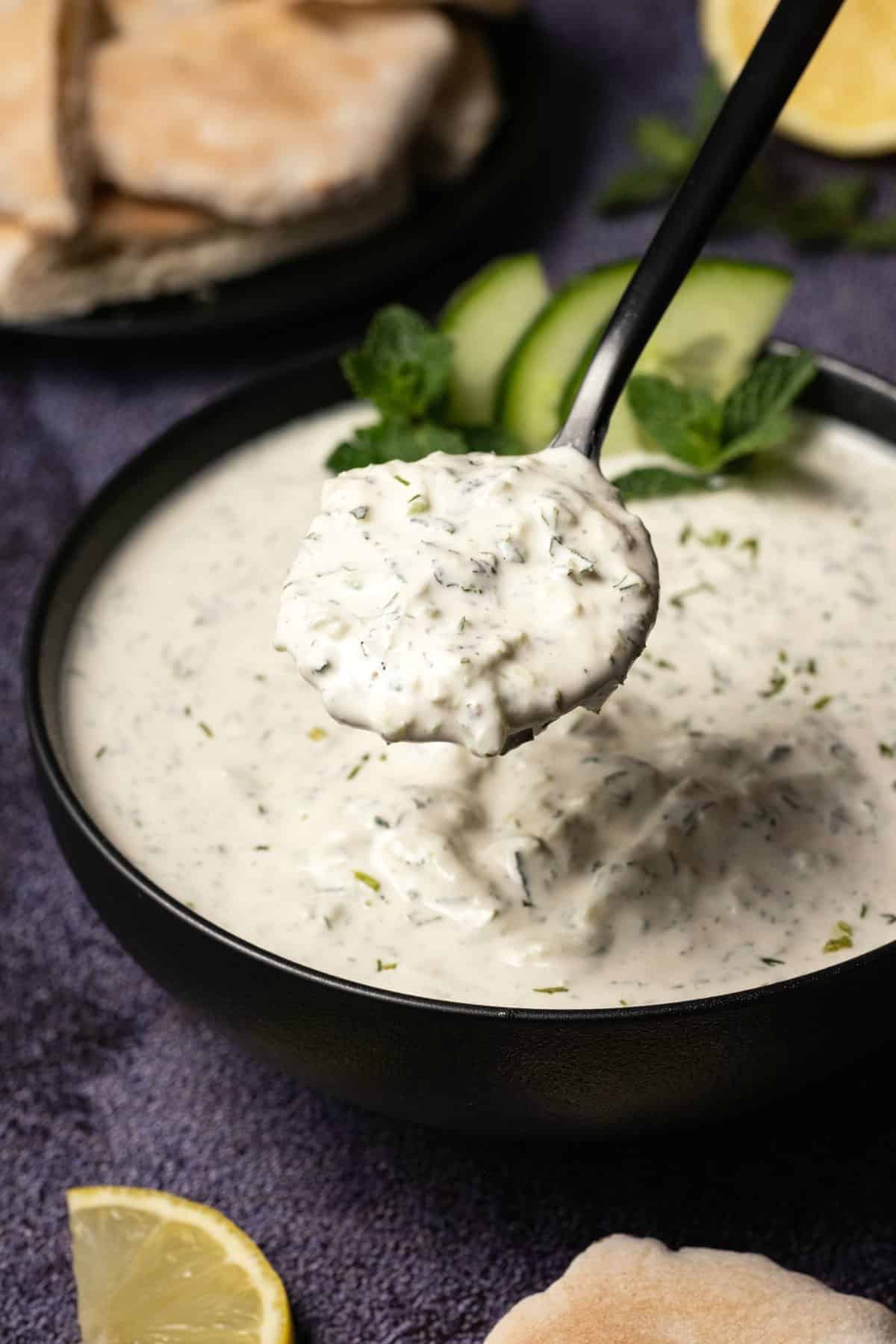 Tzatziki in a black bowl with a spoon. 